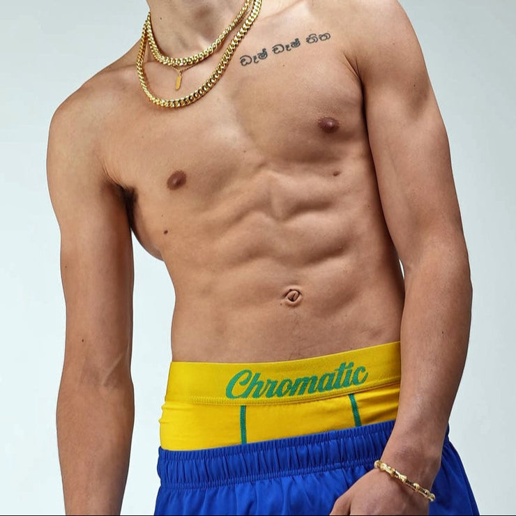 Chromaldinho models a vibrant yellow pair of Chromatic underwear, standing confidently with his torso slightly turned to highlight the bold branded waistband. The bright color pops against his skin tone, drawing attention to the clean lines and contoured fit of the briefs. Streetwear-inspired aesthetic. The lighting accentuates his physique while keeping the focus on the underwear’s sharp, flattering cut and energetic Brazil  funk vibes. Worn by Auden barnes. Unclebenmybrudda