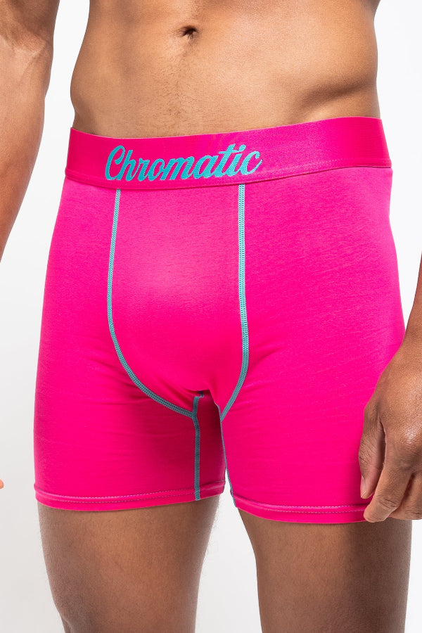 Person wearing bright pink boxer briefs with blue Chromatic logo on the waistband on a white background