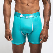 Tsunami SZN blue and white Chromatic briefs, styled with a fresh, ocean-inspired aesthetic. The icy blue waistband with bold branding contrasts against the clean white fabric, creating a crisp, wave-like vibe. He stands with relaxed confidence, water droplets on his skin catching the light to enhance the coastal energy of the look. The form-fitting cut and breathable material highlight comfort without sacrificing edge. This pair makes a splash clean, bold, and unapologetically eye-catching.