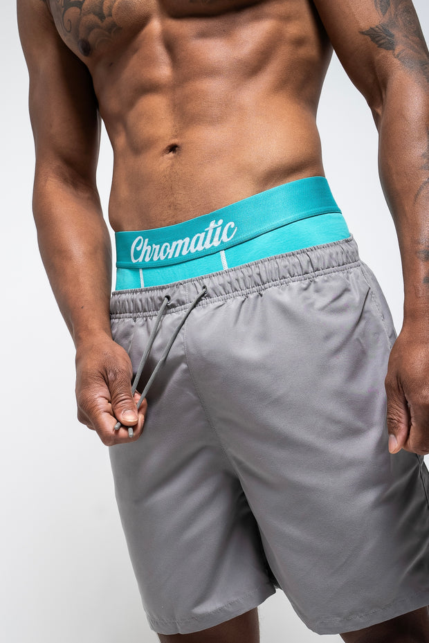 Person wearing grey shorts with a blue waistband featuring 'Chromatic' branding on a white background.